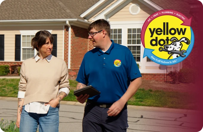A technician in a blue Yellow Dot shirt talks with a woman outside a suburban house. The Yellow Dot service logo is displayed in the corner.